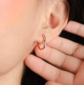 Fine jewellery, silver jewellery plated with rose gold, hypoallergenic, tarnish-free, Close-up side view of a hand holding an rose gold earring near an ear with a blurred background
